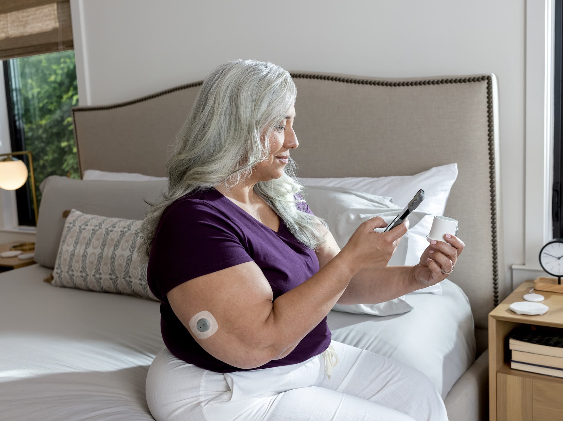Woman checking glucose readings on phone with CGM sensor visible